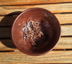 Bol à thé rouille avec des agrafes cuivrées sur une table en bois 
